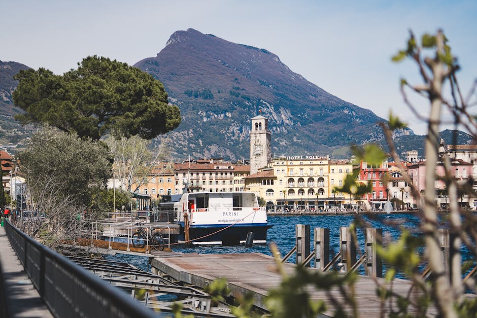 Charming lakeside town of Riva del Garda with picturesque mountains and a boat docked at the pier