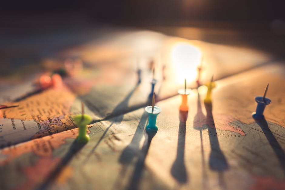 A close-up view of colorful push pins casting shadows on a world map during sunset