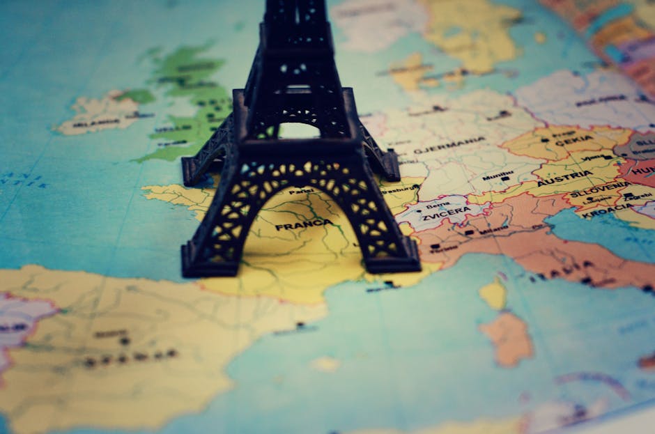 Miniature Eiffel Tower placed on a map of Europe, focusing on France